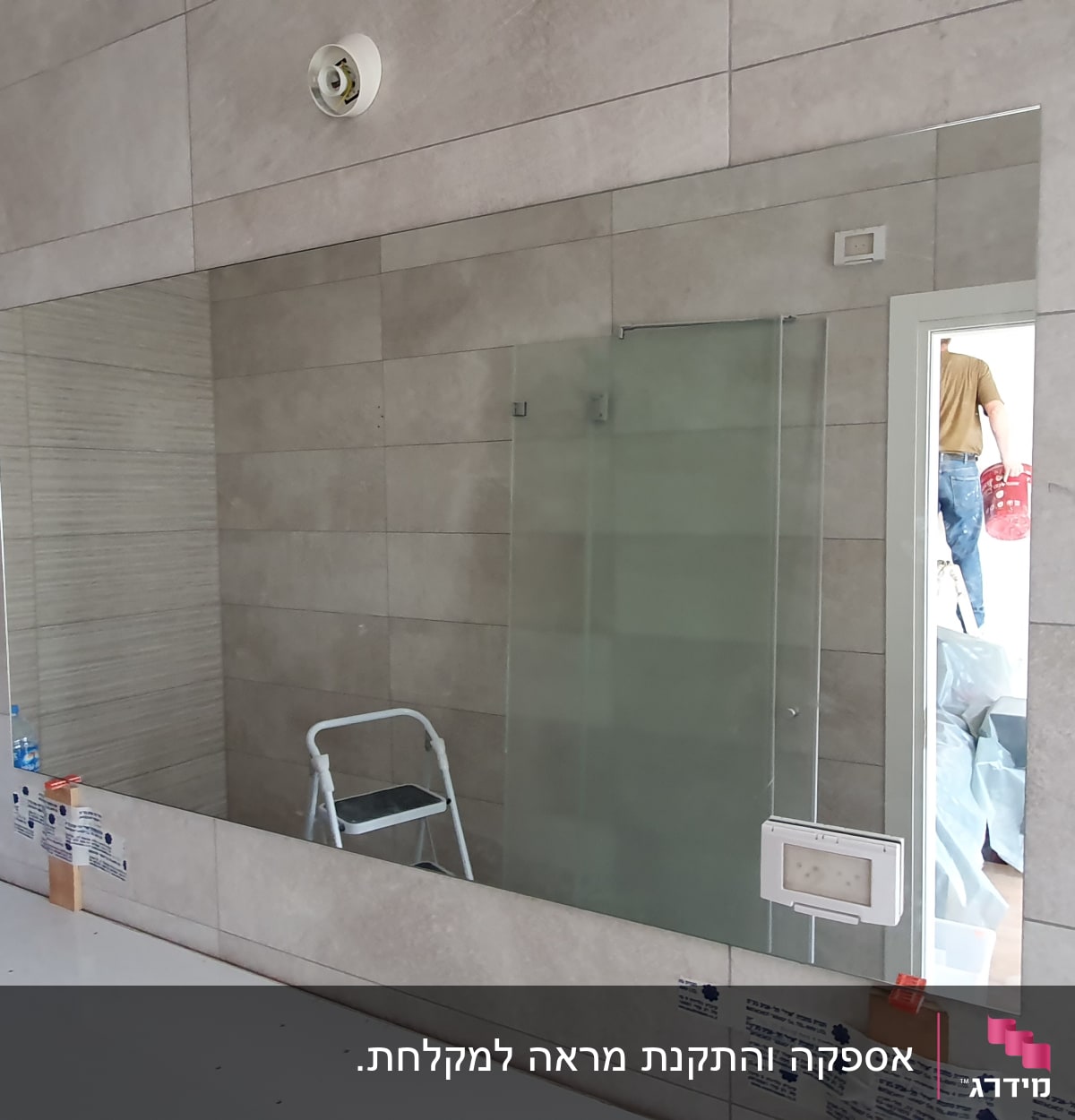 מראה גדולה על קיר עם זכוכית מקלחת